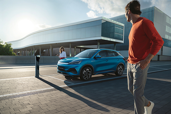 Man looking at BYD ATTO 3 and woman with charger