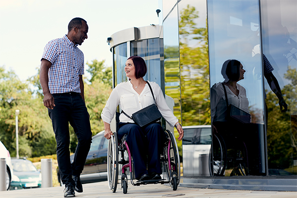 Man walking beside woman in wheelchair